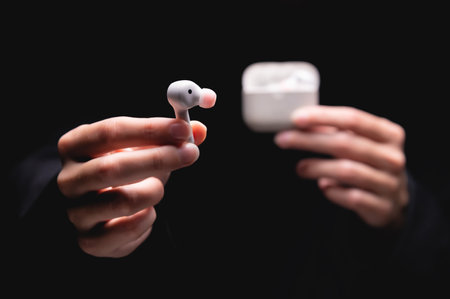 close-up of a woman taking a white wireless earphone out of the charger. Female hands touch the...