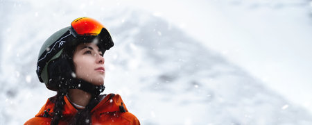 Panoramic photo of a Caucasian young woman in a ski helmet against the backdrop of a snowy landscapeの写真素材
