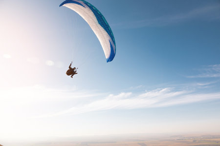 A paraglider with a blue parachute fly. A male flyght on the sky and lifts a paraglider into the airの写真素材