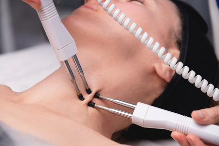 Close-up of a woman receiving an electric neck massage with equipment in a beauty salon. Used for...