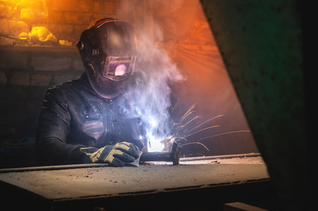 welder wearing a mask and eye protection welds a part on a pipe. Close-up of an old trowel and...