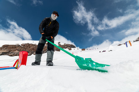 Man clears snow at a ski resort in winter. A snow park worker shapes and prepares figures for skiing