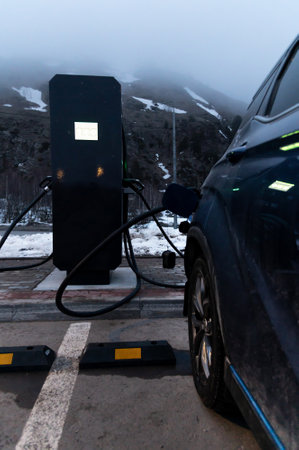 Low key. A car is parked near an electric filling station and is filling up. Electric filling...