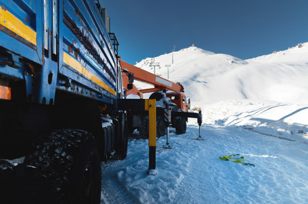 Close-up of heavy-duty truck tires against snowy landscape in industrial setting. Heavy-duty crane...