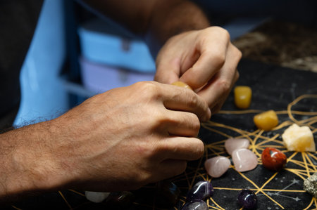 Male hands holding various fortune telling multicolored natural stones in a dark room of accult...