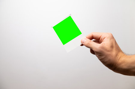 guy holds a blank instant photo card on a gray background. A man's hand shows a photographの写真素材