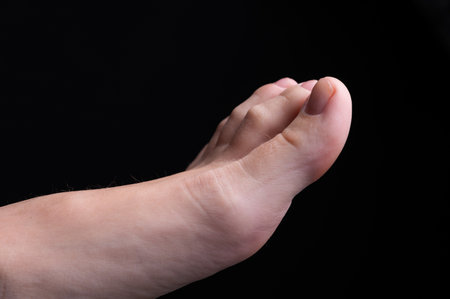 Barefoot feet, on black background. Close-up shot of healthy beautiful female feet. Health and beauty concept. Top view of human foot with neutral manicure or pedicureの写真素材
