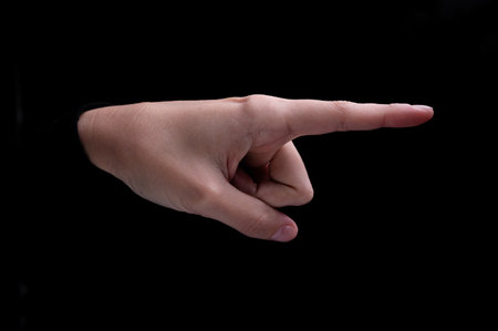 Female hand of caucasian woman pointing fingers to the right side on black backgroundの写真素材