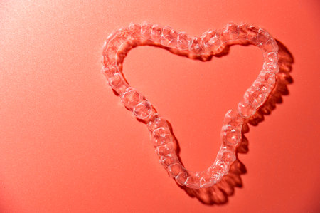 Close up of invisible aligners on pink background with copy space. Plastic braces dental retainers for teeth straighteningの写真素材
