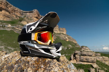 Professional full face helmet with goggles mask lies on a rock against the backdrop of a mountain...