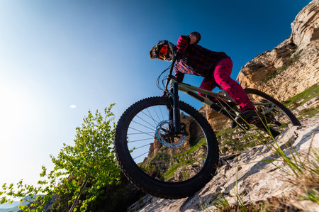 Mountain biking in the Swiss Alps. Athlete with a bicycle with a stunning view of rocky mountains and blue sky, sharp angle of the road, high-speed descent downの写真素材