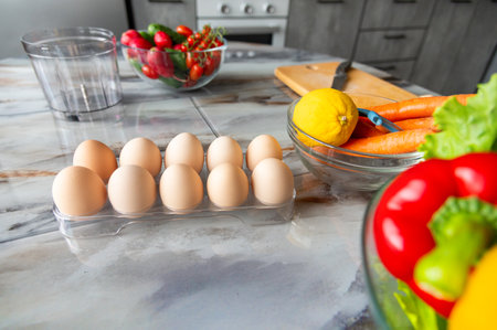 cassette of light eggs, a dozen fresh chicken eggs stand on the table in a plastic container among vegetables and food productsの写真素材