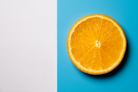 Whole orange slice, on blue and white background. Top view. Flat lay, mockup for textの写真素材