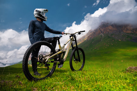 Young unrecognizable man standing near mountain bike in field. Cyclist standing on mountain bike wearing helmetの写真素材