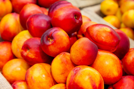 Close-up a lot of fresh red yellow colored peaches on market stall or in groceries shop area. Nectarines background. Fruit food background. Selective focusの写真素材