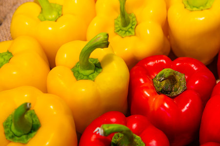 Close-up of many red and yellow bell peppers in a stall at the market. Vegetarian background. Rich...