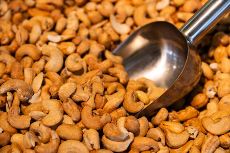 Metal scoop surrounded by roasted cashew nuts. Close-up. Background for snacks and nutsの写真素材