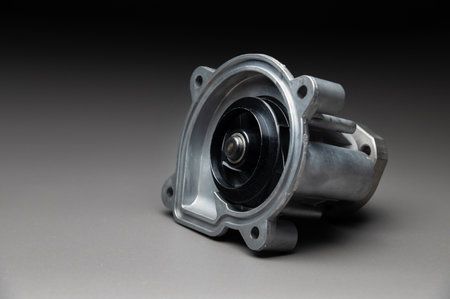 A new car part on a gradient gray background. Close-up of a new internal combustion engine coolant pump. Contrast backlighting.の写真素材