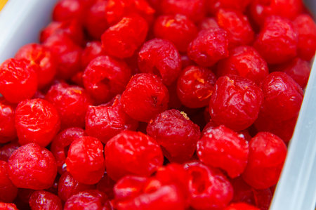 A close-up of a large number of caramelized cherries on a store shelf. Translucent cherries coated...