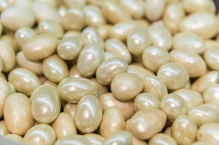 pile of candied almond dragees serves as a backdrop. Handmade nut candies in white chocolateの写真素材