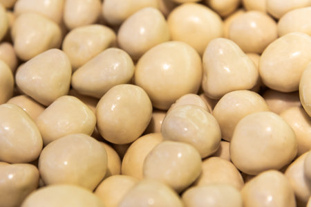 pile of candied almond dragees serves as a backdrop. Handmade nut candies in white chocolateの写真素材