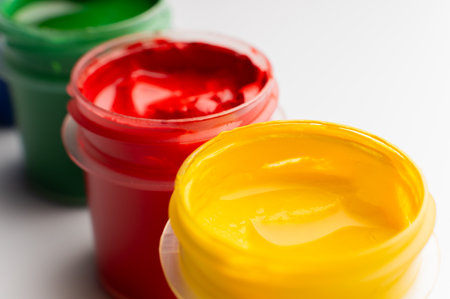 A close-up macro shot of open gouache paint jars. Multicolored paints in plastic jars with a shallow depth of field.の写真素材