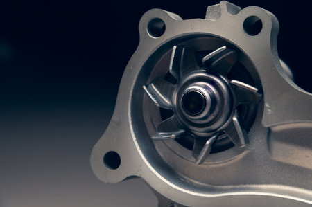 Close-up of a new internal combustion engine cooling water pump on a gray background.