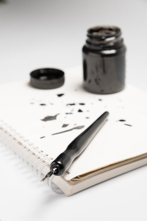 A fountain pen lies on an ink-splattered notebook next to a bottle of ink.の写真素材