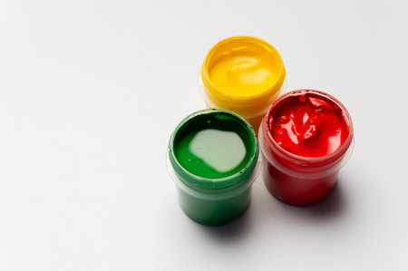 Jars of multi-colored gouache on a white background. Green, red, and yellow.の写真素材