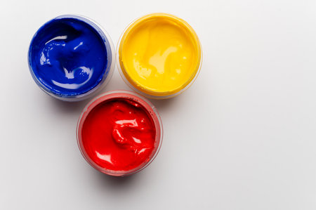 Jars of multi-colored gouache on a white background. Blue, red, and yellow.の写真素材