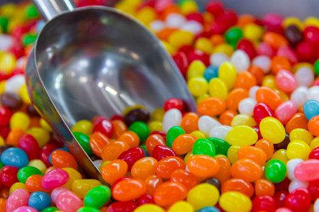 Glazed beaded candies on a store counter with a scoop dipped in. Many colorful candies in soft focus.の写真素材