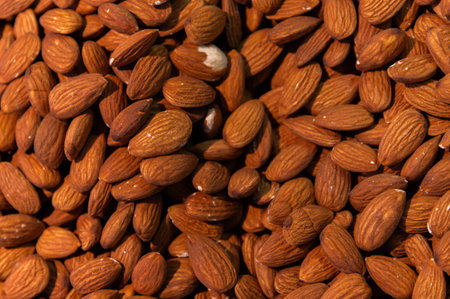 Delicious roasted almonds with spices are sold in large quantities at a vegetable market. Close-up....