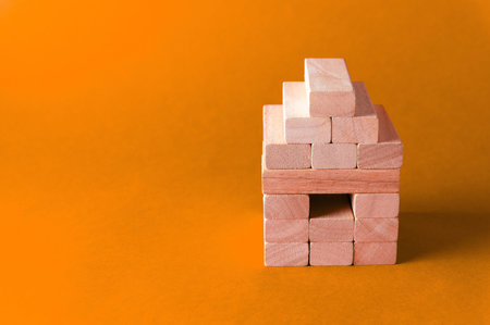 A metaphorical model of a wooden house on a colored background with copy space. Housing and real...