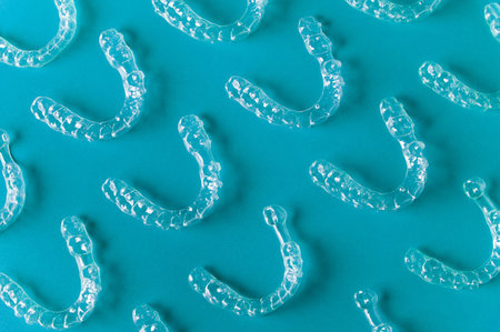 Clear dental aligners arranged on a blue background, showcasing their transparent design and unique...