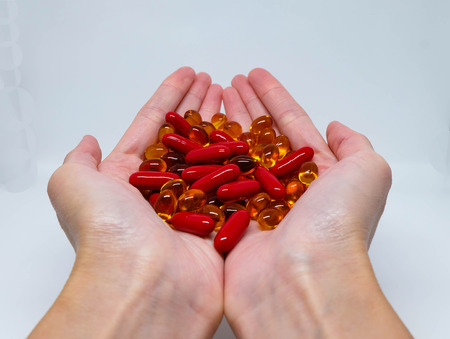 A pile of red and yellow capsules in palmの写真素材