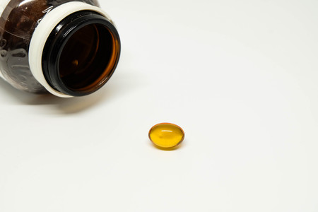 Brown medicine glass bottle with a yellow softgelの写真素材
