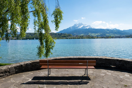 Bench faces to Geneva lake and alps landscape view during sunny day.の写真素材