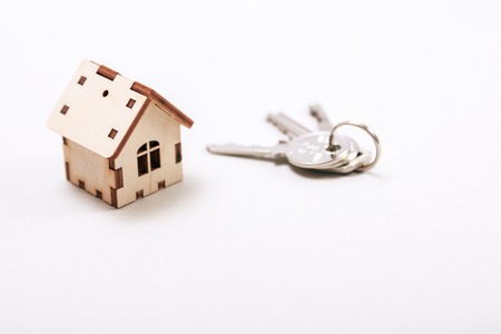 Wooden miniature house with door keys close up. Real estate concept. Small toy wooden house with keys with copy space.の写真素材