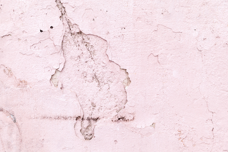 Pink plaster wall with cracks and chips. Abstract background. Wall texture pink building with a crack in the form of a hippopotamus close-up background for designの写真素材