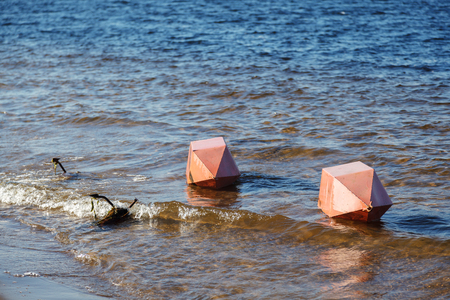 Safety on the water. Two large orange buoys and an anchor lie horizontally at the shore on the water of the river Bayの写真素材