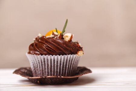 Delicious cupcake with whipped cream and chocolate on a blurred background of beige wall. Concept of advertising confectionery productsの写真素材