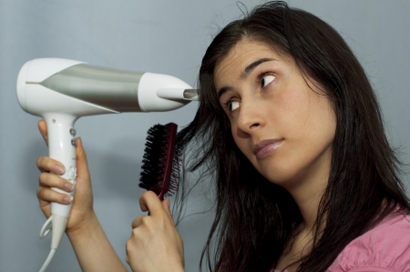 Young woman dries the hair dryer long dark hairの写真素材