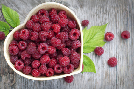 Raspberry in plate in form of heart on wooden tableの写真素材