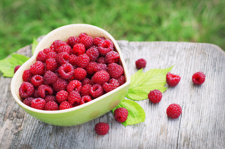 Raspberry in green bowl on wooden backgroundの写真素材