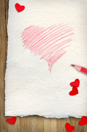 Red drawn heart and red pencil on old paper and wooden backgroundの写真素材