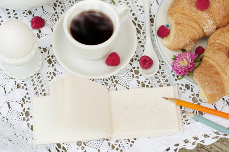 Breakfast with cup of coffee. A dessert with croissants and berries of raspberry on white a lace tableclothの写真素材