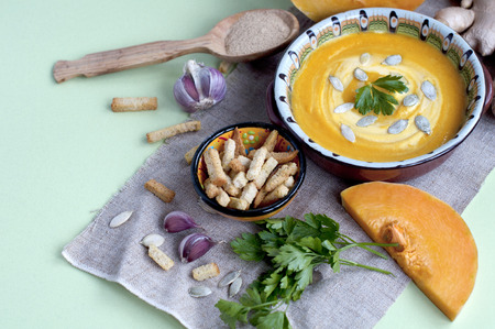 Pumpkin cream soup with crackers and ginger, parsley and seedsの写真素材