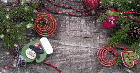 Christmas card with decorative symbol: fir-tree branches, snowman, gift, curl, cones on a wooden background.の写真素材