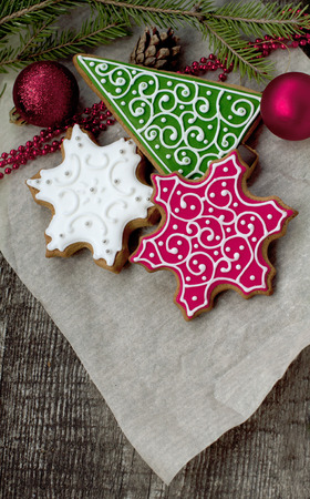 Christmas gingerbreads in the form of white and red snowflakes and a green fir-tree on parchment paperの写真素材