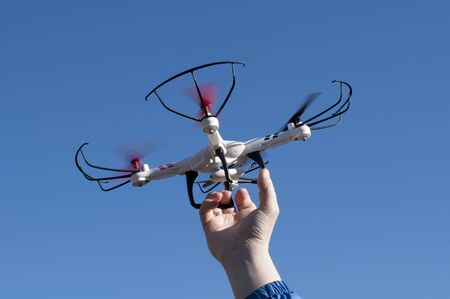 Quadcopter in hand against blue skyの写真素材
